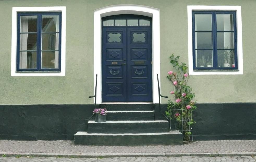 grönt-putshus-med-blå-fönster-och-dörr